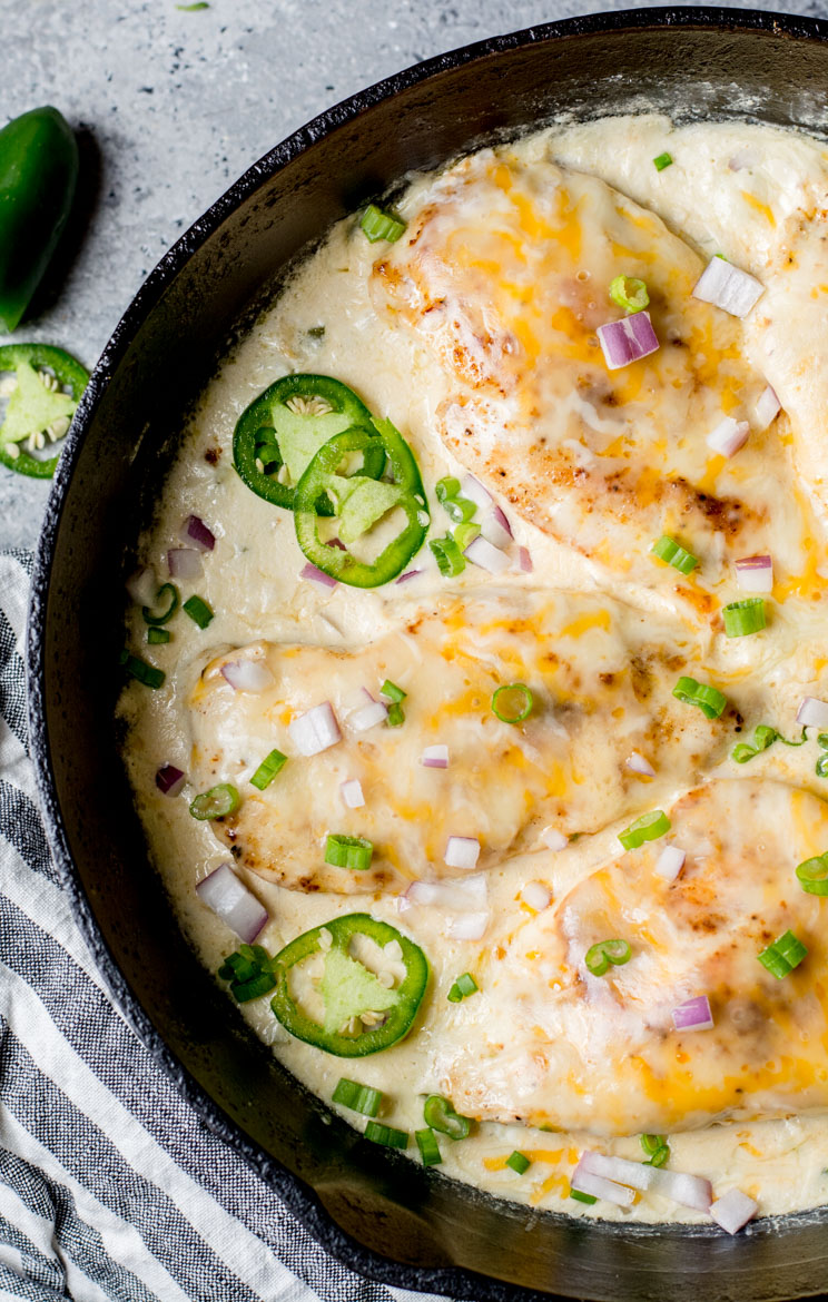 An image displaying a One Pan Keto Cheesy Jalape&ntilde;o Chicken dish - a tantalizing entree composed of tender chicken breast cooked to perfection and smothered in a creamy sauce with cream cheese, cheddar cheese, and spicy jalape&ntilde;o. Other ingredients like onion, butter, and garlic enhance the dish's savory allure. It's served hot from the skillet, capturing the simplicity of its 16-minute preparation. The overall look of this dish signals a perfect low-carb dinner or an easy keto meal prep solution.