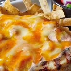 Image displaying Applebee's Fiesta Lime Chicken, a tantalizing dish featuring a grilled chicken breast glazed with a zesty cilantro lime dressing, topped with pico de gallo, seasoning, and shredded cheese, offering a keto-friendly option when served without rice, tortillas, or ranch dressing.